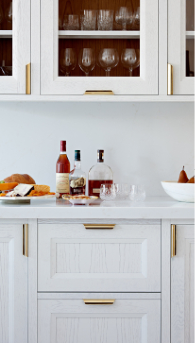 White base cabinets with alcohol bottles on it and wall mounted white cabinets with glass doors and alcohol bottles in them 