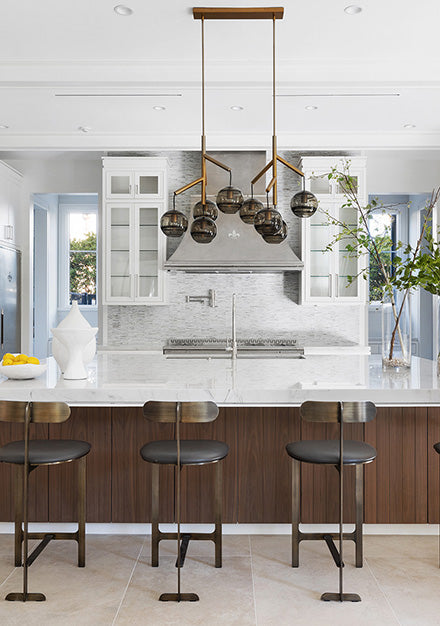 Wooden Base Kitchen Cabinets With Marble Countertop In the middle of the Kitchen. Silver Luxury Kitchen Range Hood in between White Wall Cabinets