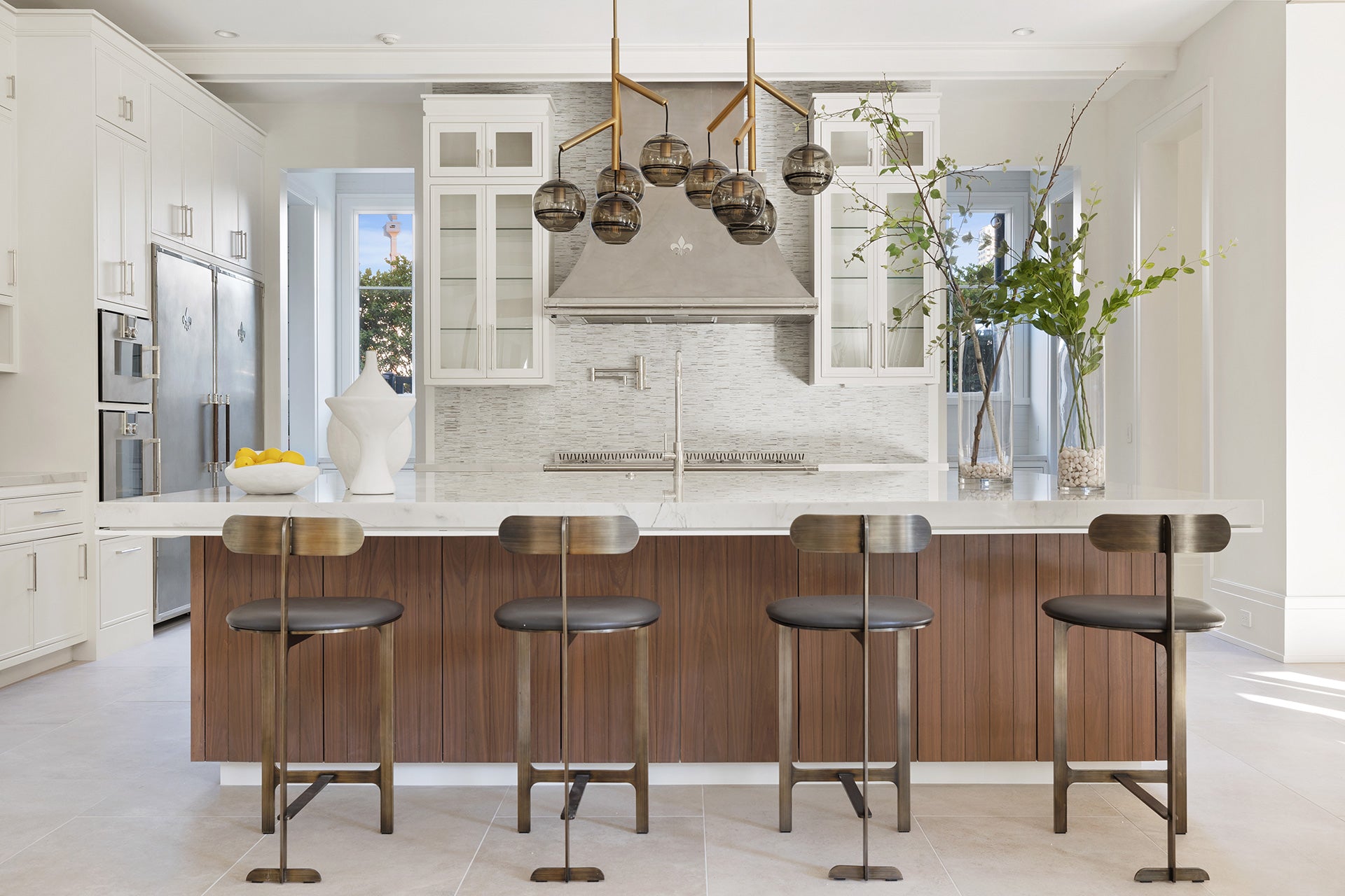 Wooden Base Kitchen Cabinets With Marble Countertop In the middle of the Kitchen. Silver Luxury Kitchen Range Hood in between White Wall Cabinets