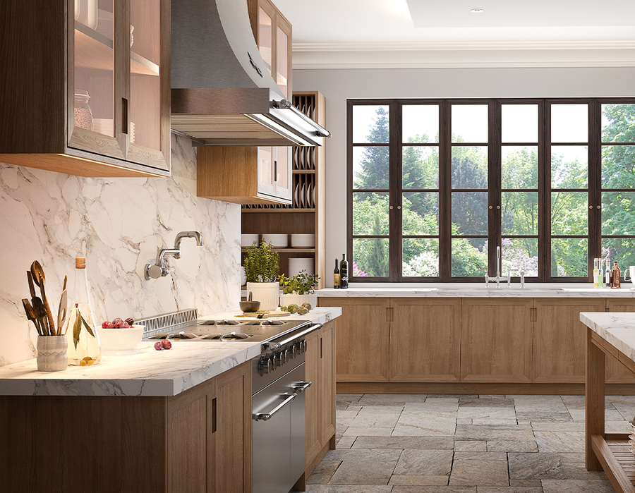 A wide shot of an elegant, transitional kitchen with natural wood cabinetry, a stainless steel professional range, and a dramatic white marble backsplash and countertops. A large, dark-framed window offers a picturesque view of the outdoors, and the floor is covered in large, rustic stone tiles.