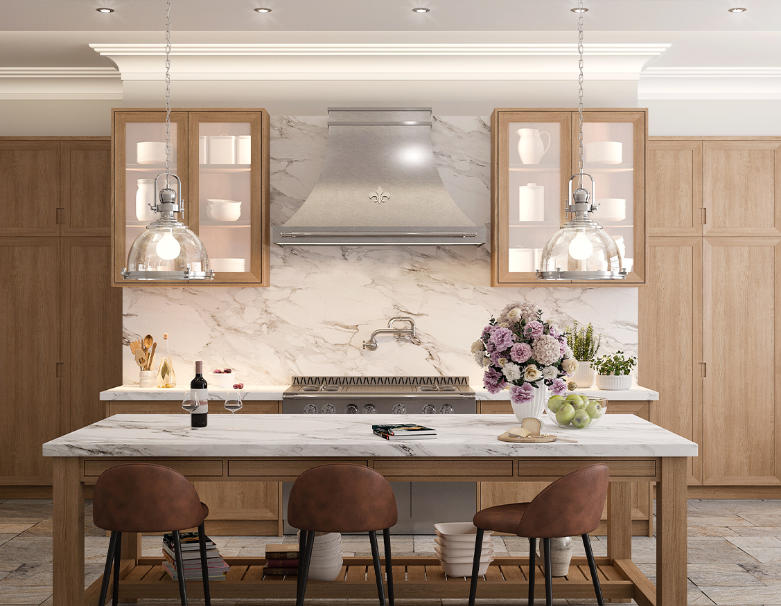 A well-lit, transitional kitchen featuring natural wood cabinetry, a white marble backsplash and countertops, and a stainless steel range and hood with a decorative fleur-de-lis. A large wood and marble island provides seating with three brown leather bar stools and is lit by two industrial-style glass pendant lights.