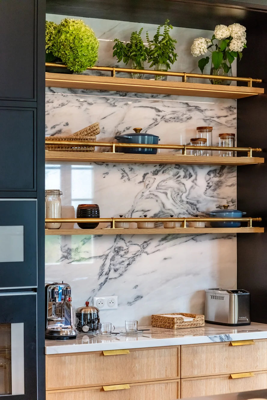 Custom Kitchen Design open shelving with brass rails against a marble slab backsplash.