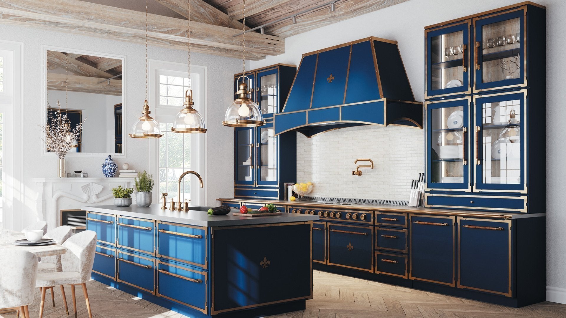 A striking, luxurious kitchen featuring deep blue cabinetry and a professional range hood accented with polished brass trim and fleur-de-lis emblems. The space includes a large kitchen island with a dark countertop and a brass faucet, a white brick backsplash with a brass pot filler, and a rustic exposed beam ceiling above a light wood floor.