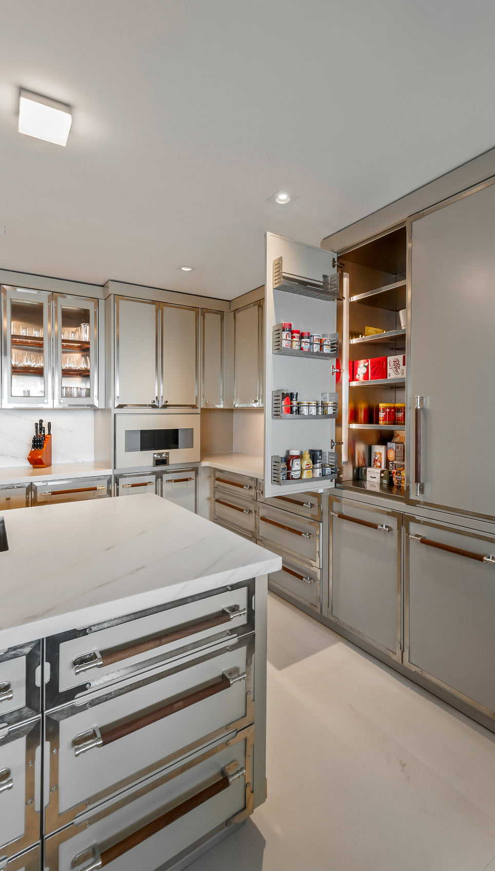 Luxury modern galley kitchen with metallic champagne cabinets, white marble countertops, and professional range stove.