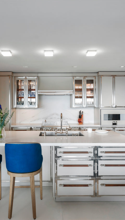 Modern kitchen island with a white quartz countertop and two vibrant blue velvet bar stools in an open-concept living space.