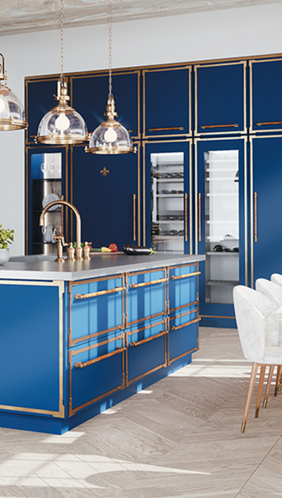 A vertical shot of a luxurious kitchen featuring a blue island with gold trim and a fleur-de-lis emblem, a gold faucet, and three glass pendant lights overhead. In the background, a wall of built-in blue appliances with gold framing, including a glass-front wine cooler, creates a dramatic statement alongside a white dining table with plush chairs.
