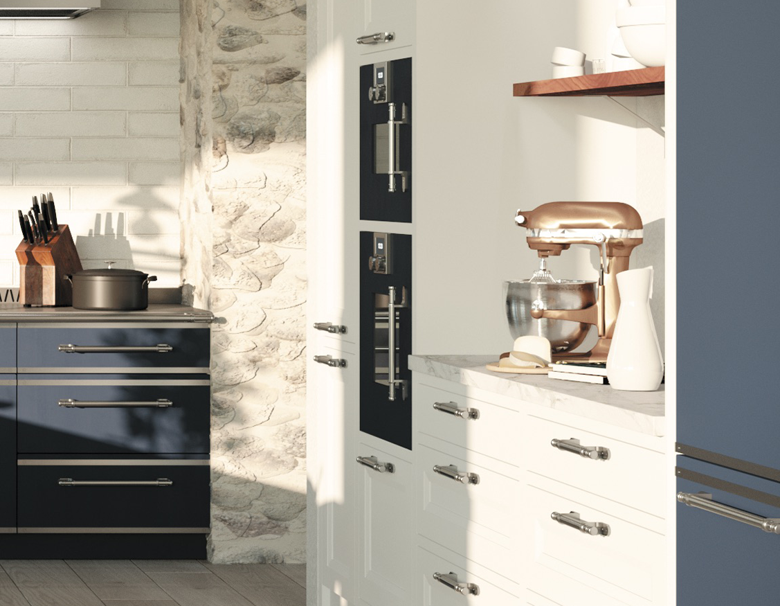 Close-up of white kitchen cabinetry with built-in double black ovens and a rose gold stand mixer on a marble countertop, adjacent to navy blue base cabinets and a rustic stone and white brick wall.