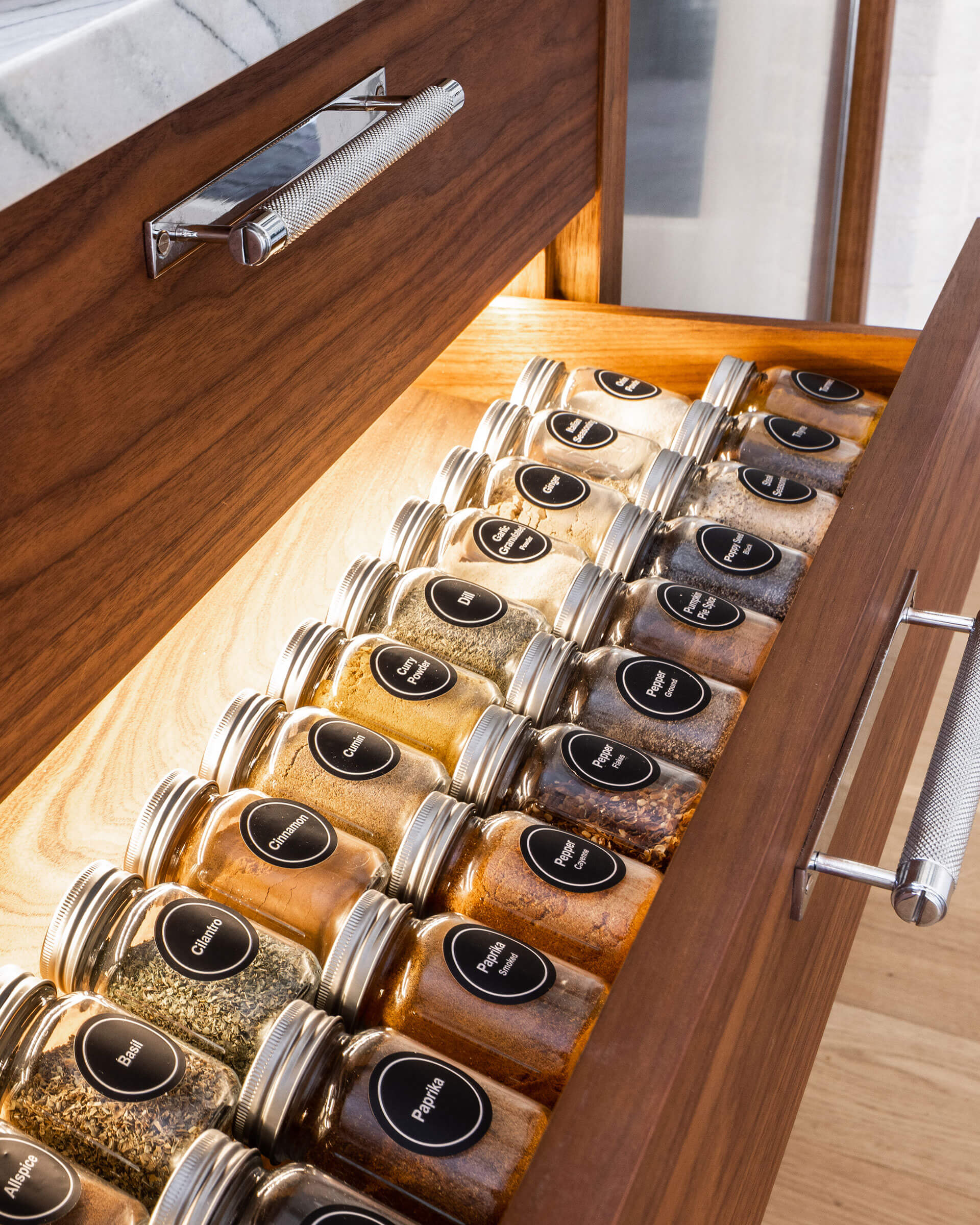 Spices bottles with silver lid in a wooden drawer storage with a silver handle