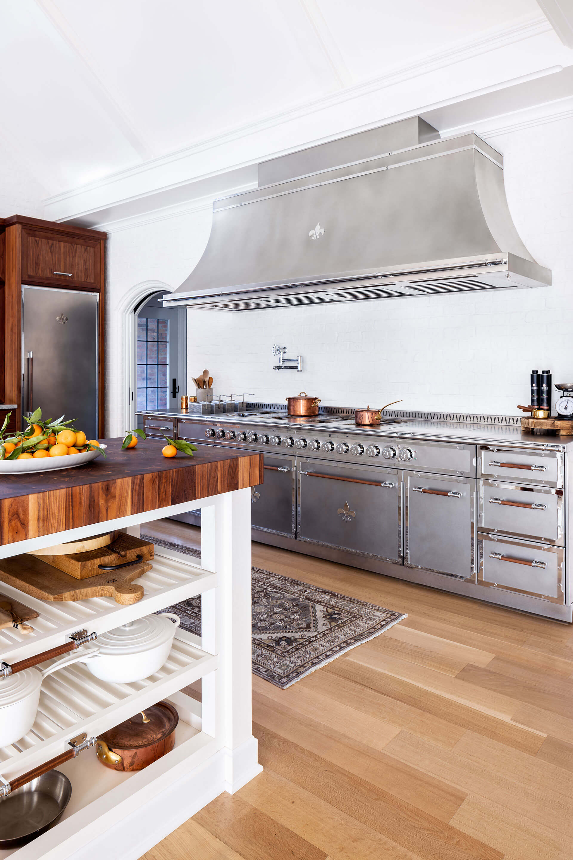 Silver Kitchen Ranges and a custom hood. Wooden white open cabinet to keep utensils