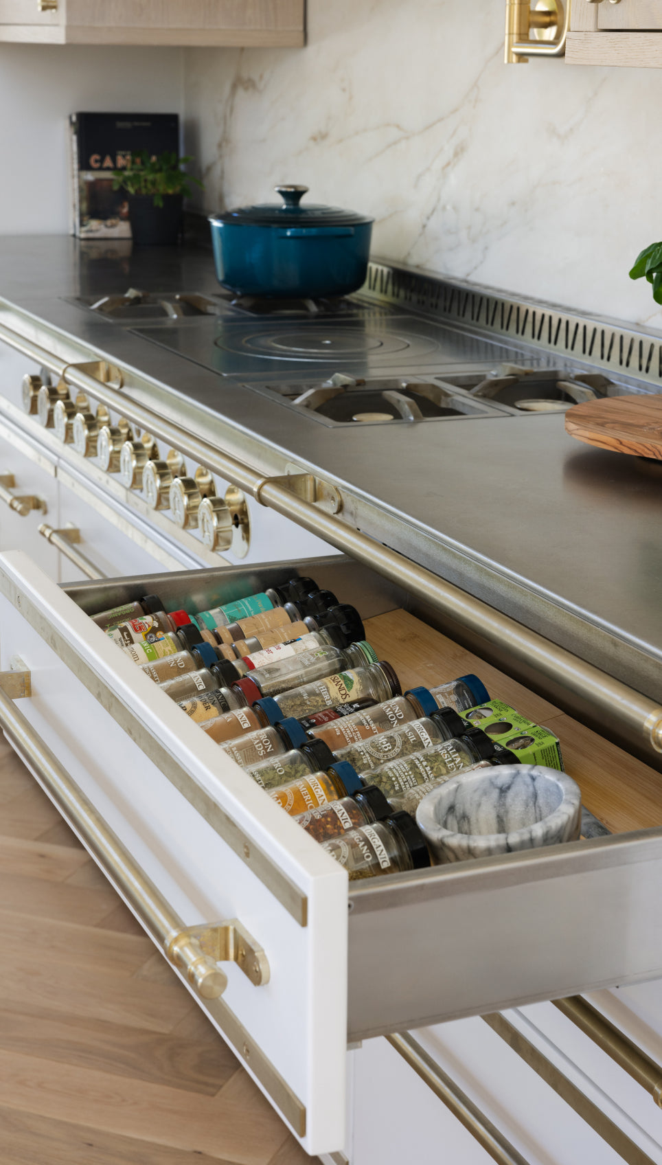 Modern kitchen with a stainless steel stove and open drawer neatly organized with spice jars