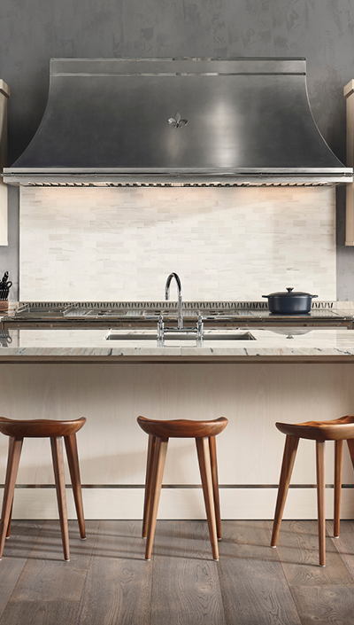 Off White Base Kitchen Cabinets With Marble Countertops and Wooden Stools. Silver Kitchen Hood in between Off White Wall Cabinets