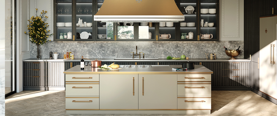 Elegant contemporary kitchen featuring a large light beige kitchen island with an integrated cooktop and brass hardware, a gold range hood, dark grey glass-front upper cabinets, and a grey marble backsplash and counter, highlighting Art Deco or Parisian apartment style.