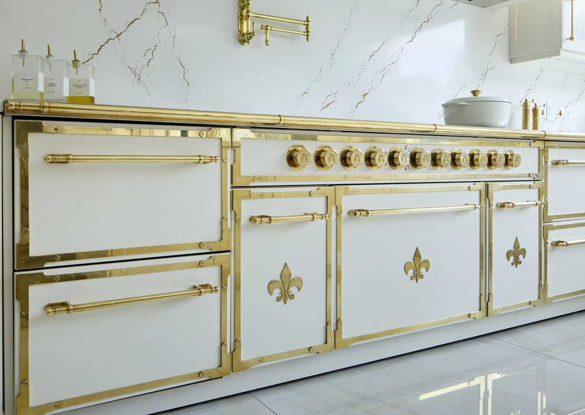 Custom French Range in white with gold fleur-de-lis detailing and marble backsplash.