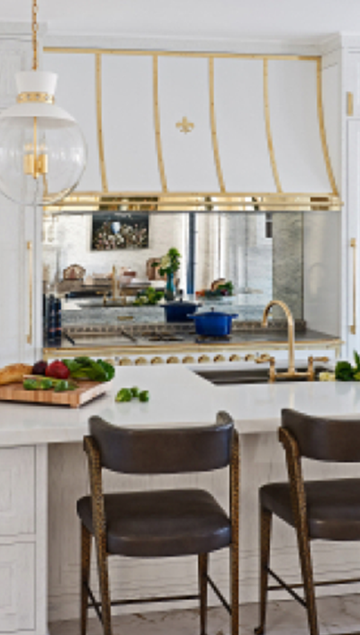 White Kitchen Base Cabinets With White Countertop and Wooden Chairs near the Countertop. White Kitchen Hood in between White Wall Cabinets