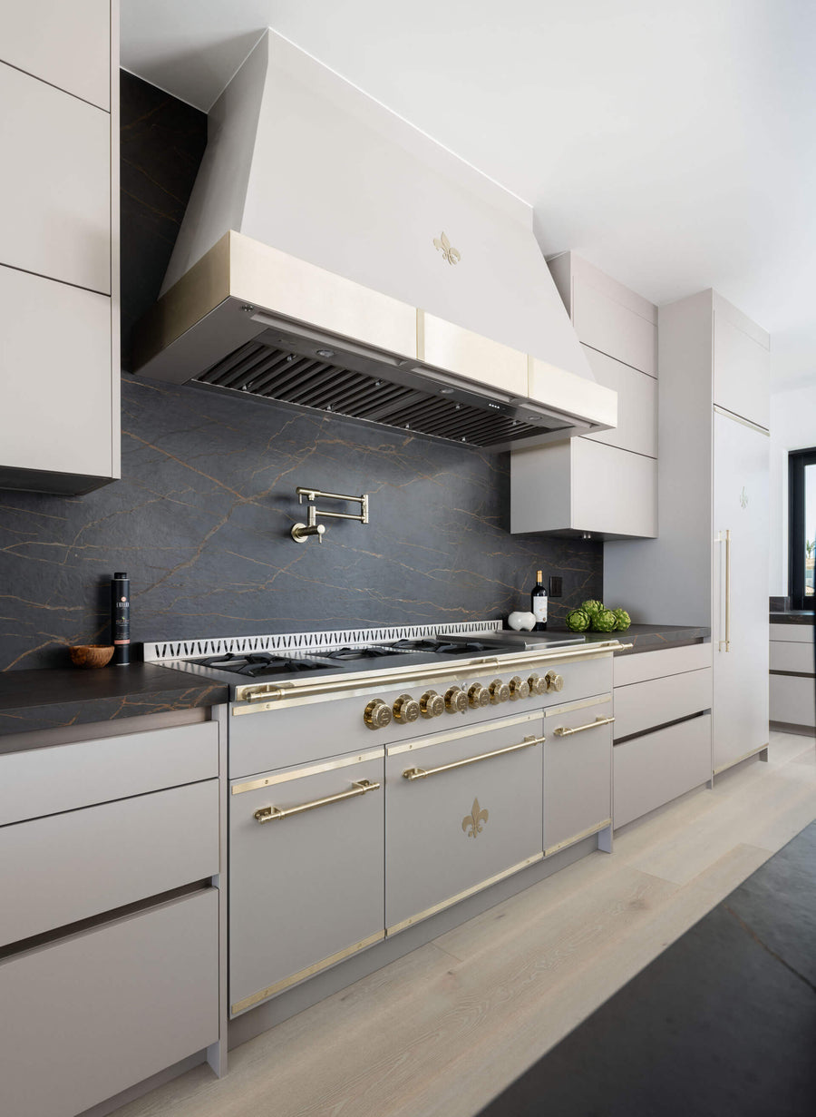 White custom kitchen ranges with white kitchen hood in between white hanging cabinets and marble countertops with French kitchen ranges
