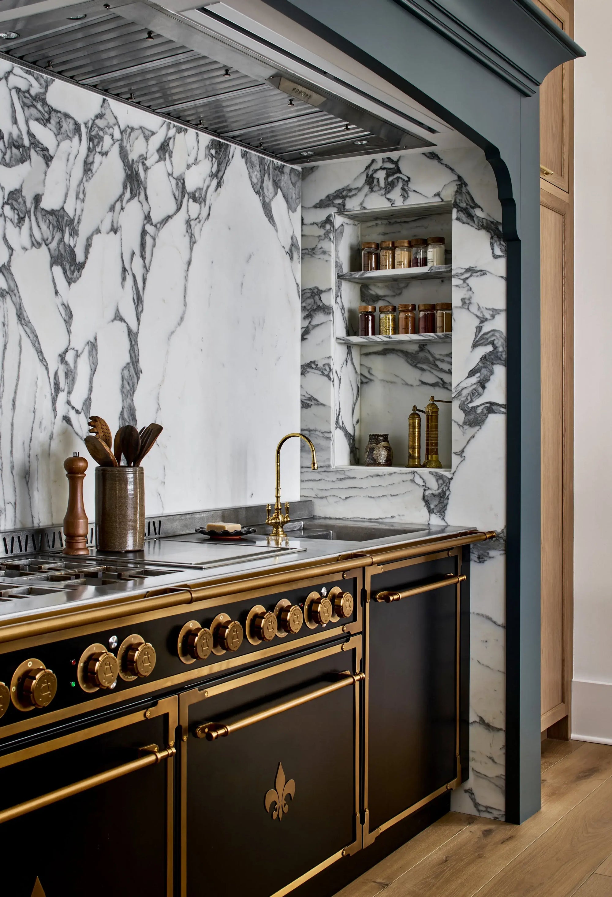 Luxury black French kitchen range with brass accents and marble backsplash in a custom English estate revival kitchen