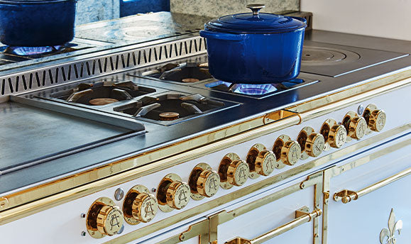 Off white and Golden French Cooking Range With Blue Color Cookware on a Gas Stove