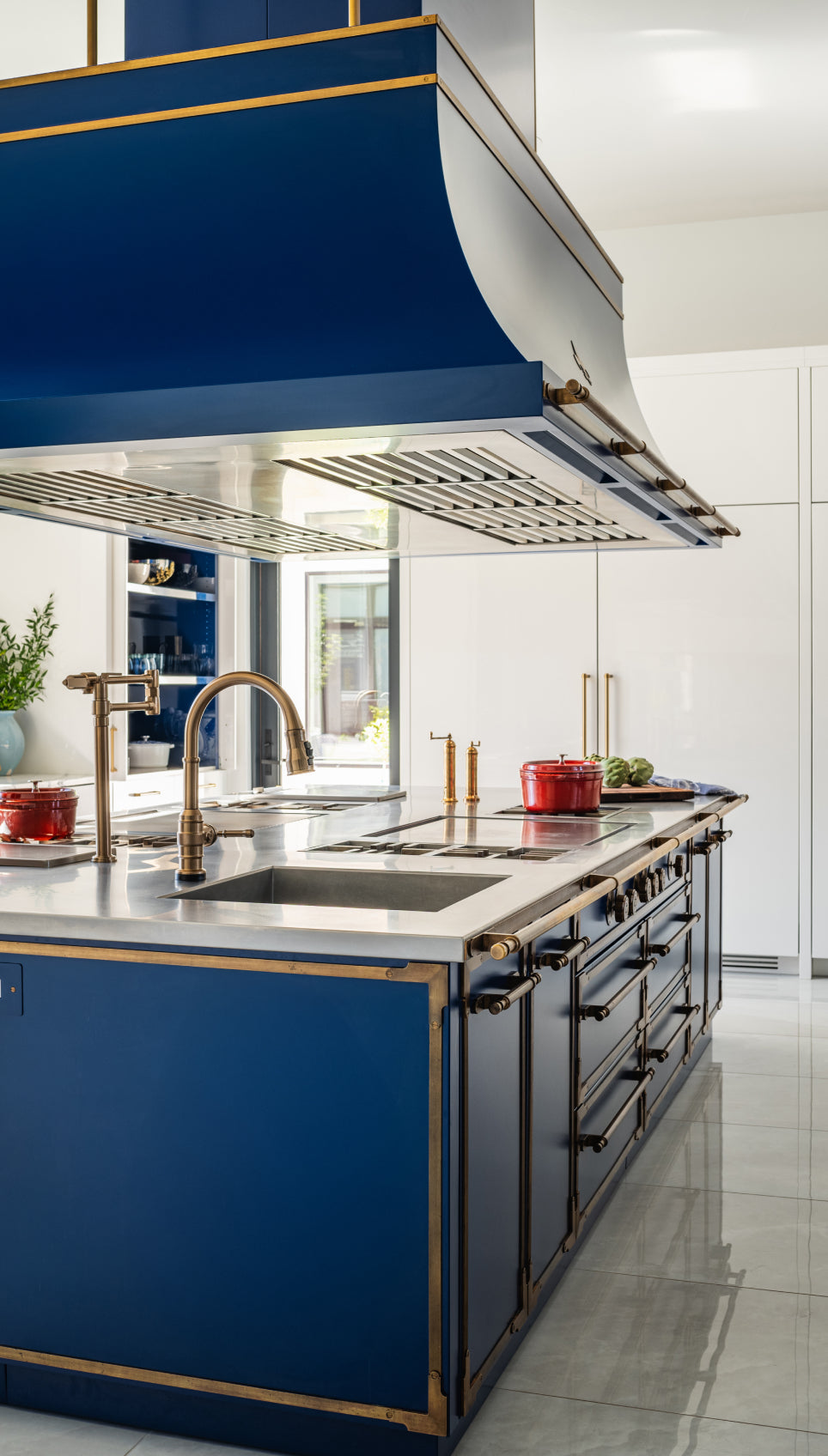 Luxury blue French kitchen range with brass accents, marble countertop, and modern hood in a premium kitchen setting