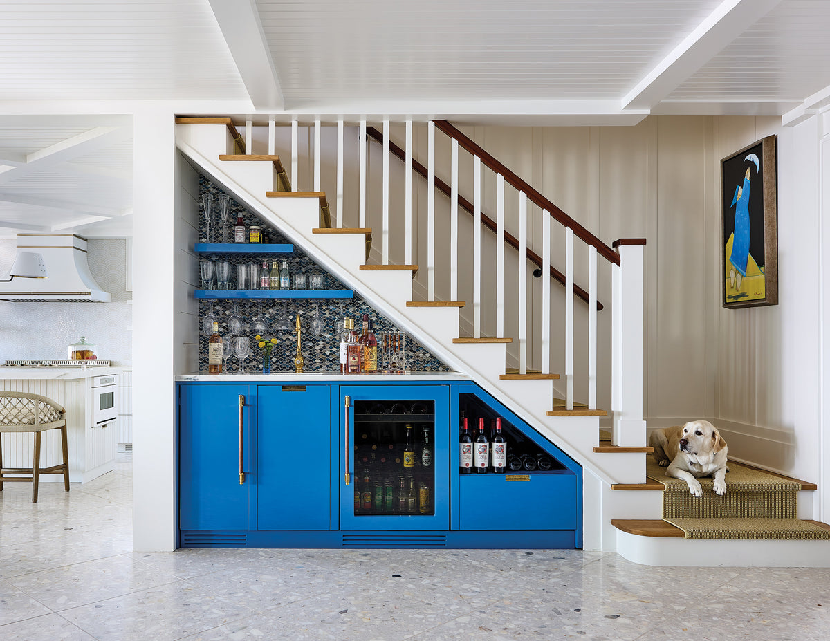 Custom under-stair blue bar with wine fridge, mosaic backsplash, and glass shelving.