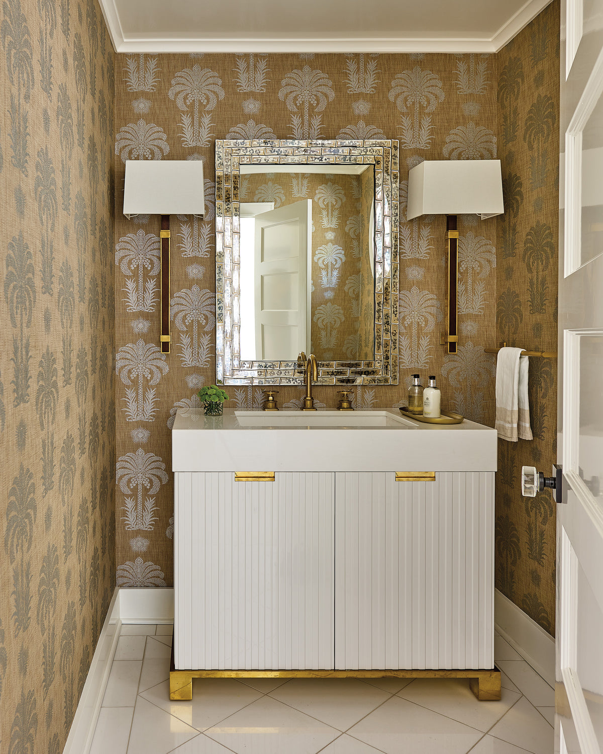 Elegant vanity nook featuring palm-motif wallpaper, an ornate mother-of-pearl mirror, and brass fixtures.