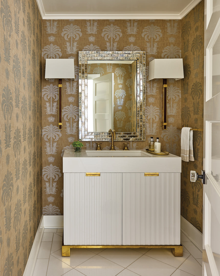 Elegant vanity nook featuring palm-motif wallpaper, an ornate mother-of-pearl mirror, and brass fixtures.