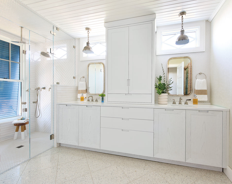 Spa-style bathroom with dual vanities, herringbone shower tile, and pendant lighting.