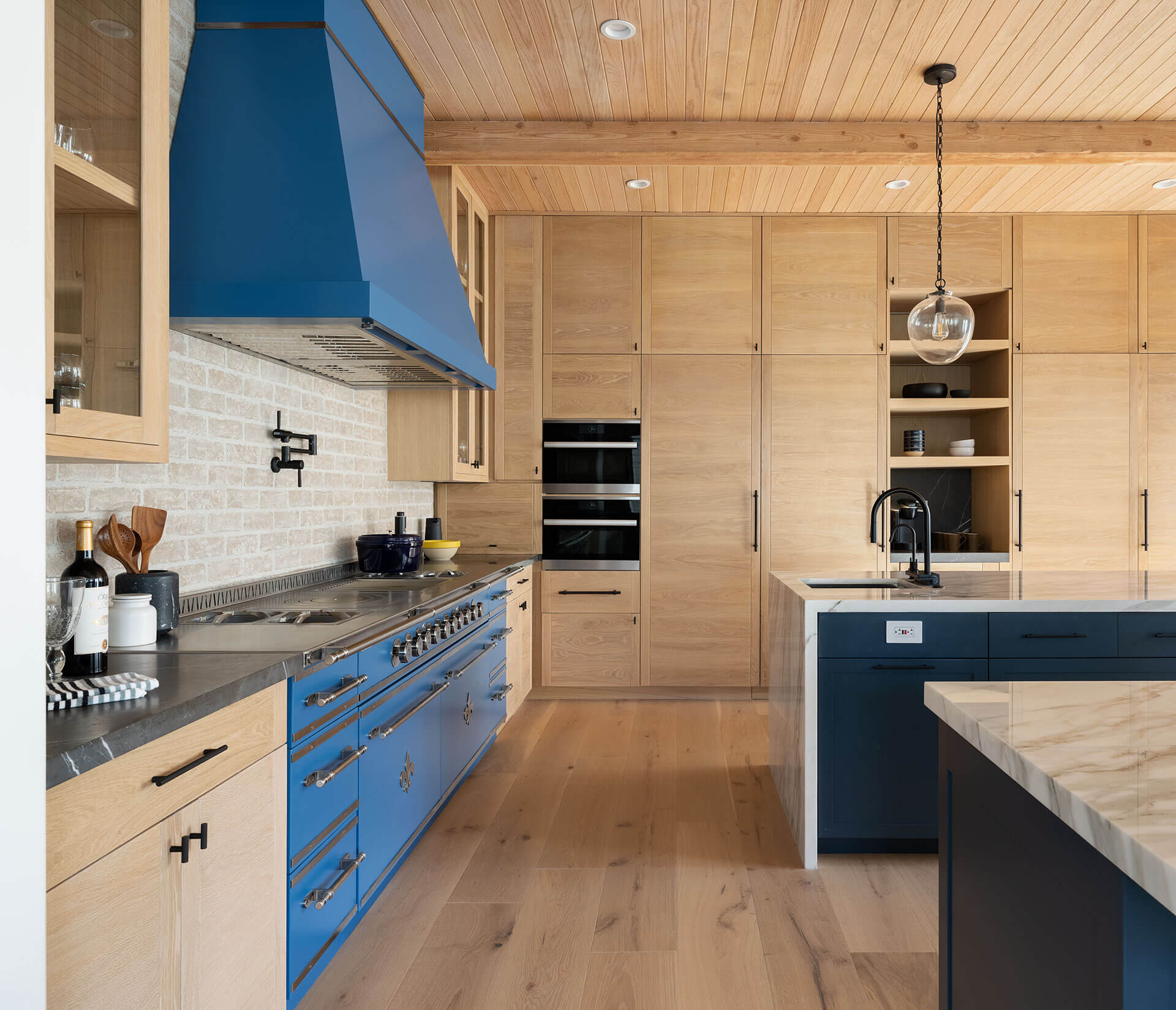 Wooden kitchen cabinets with wall mounted oven and blue French kitchen ranges and blue custom kitchen hood