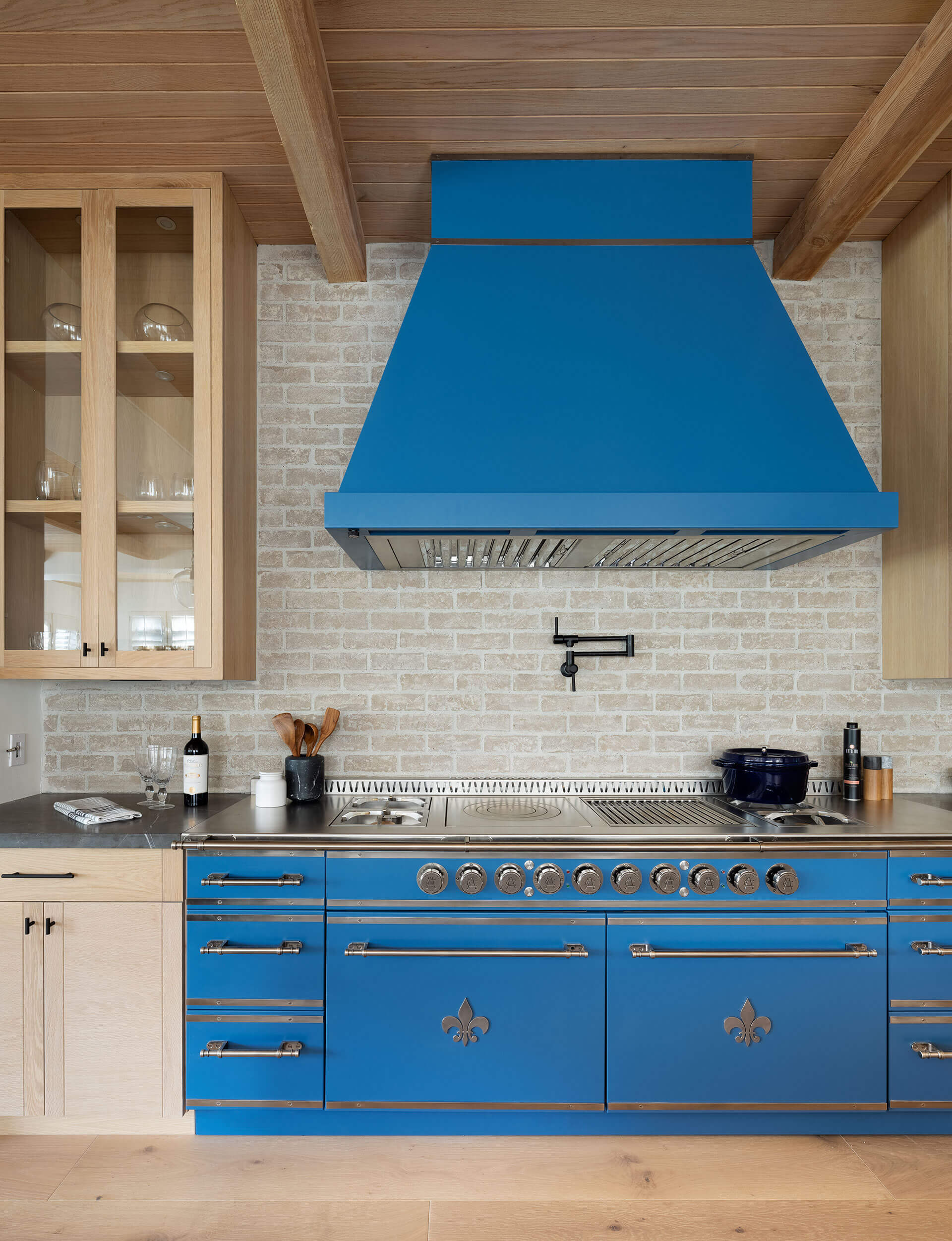 Wooden hanging custom kitchen cabinets and blue luxury kitchen hood attached to wooden ceiling