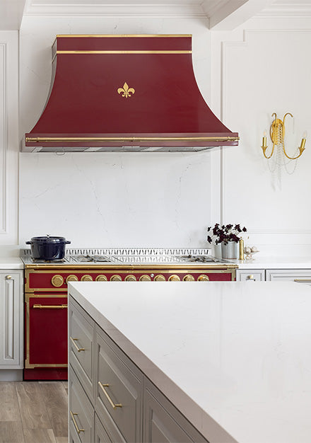 A kitchen with white cabinets and red custom hood